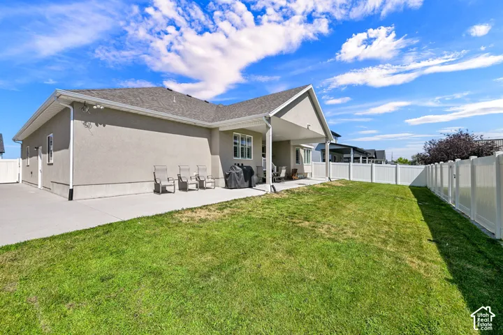 Expansive backyard featuring a lush lawn, privacy fencing, and a concrete patio