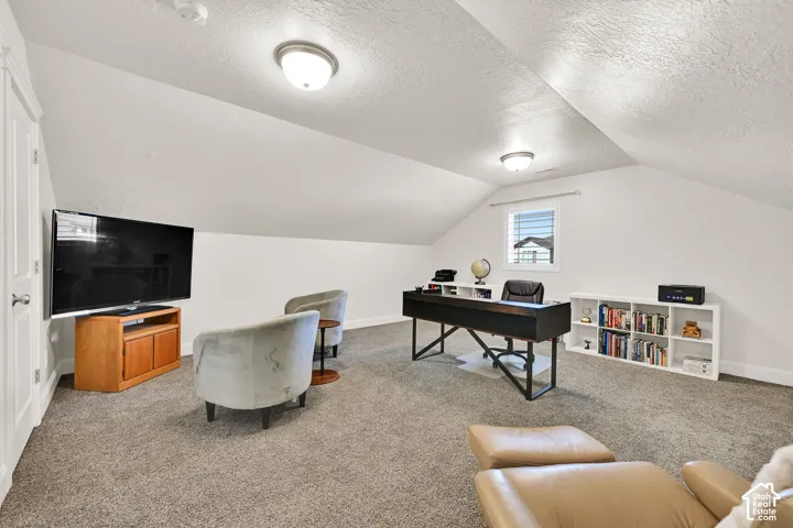 Carpeted room with vaulted ceilings and recessed lighting