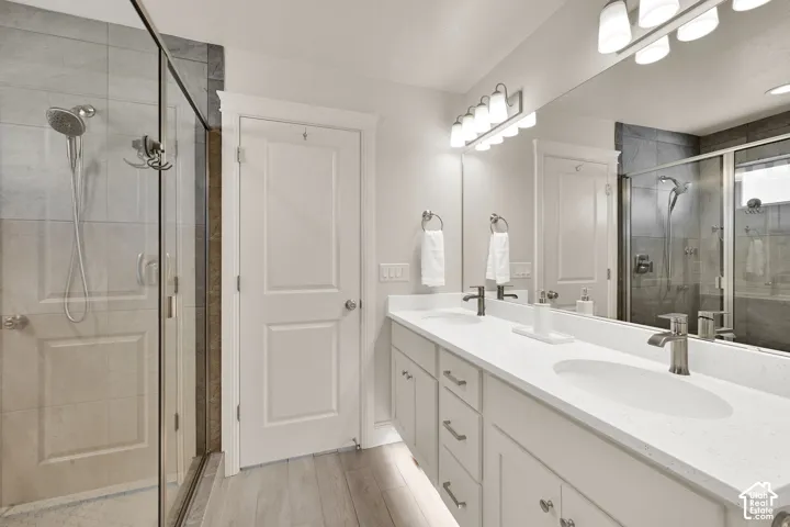 Dual vanity with white cabinetry and integrated sinks, complemented by a frameless mirror and a six-light vanity fixture