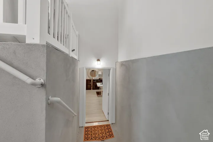 Staircase with painted wood railing, white wall paneling, and a painted pipe handrail