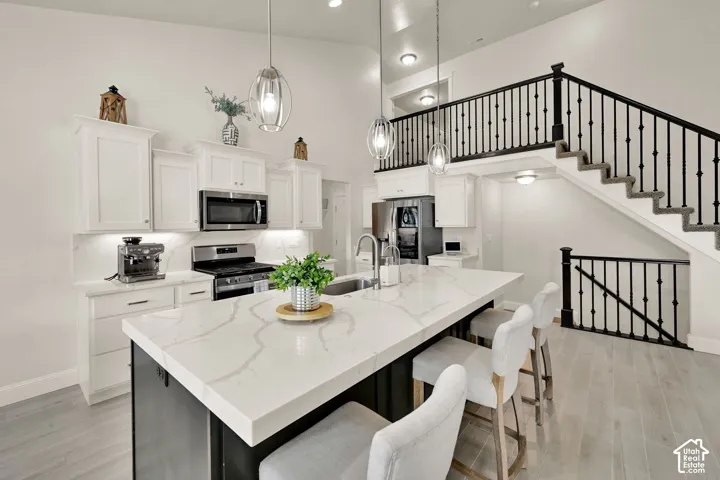 Kitchen island with light-toned countertop, integrated sink, and pendant lighting