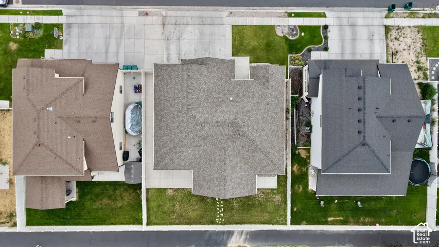 Aerial overview showcasing a property with a light brown shingle roof, green lawn, and a concrete driveway