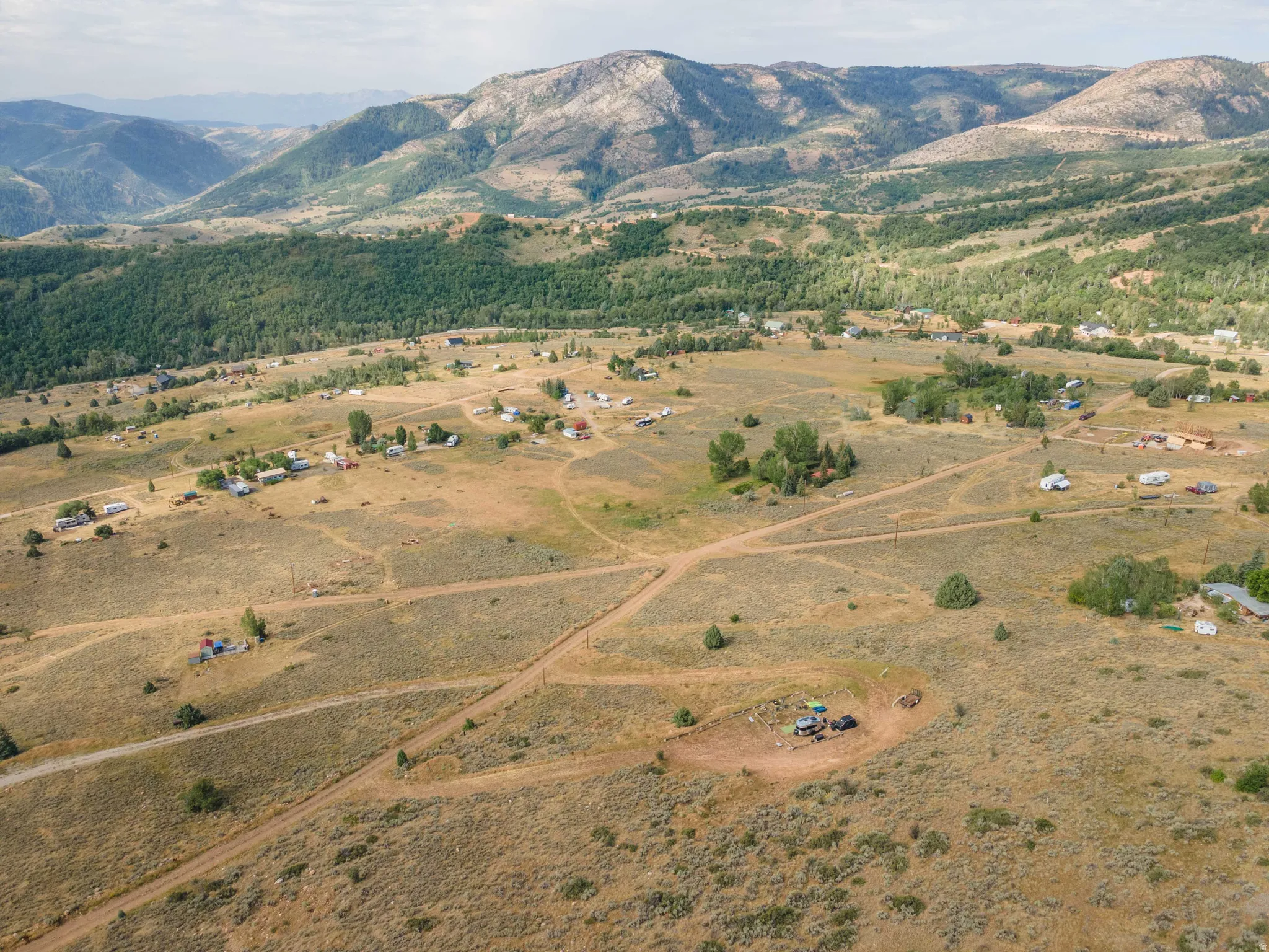Expansive mountainous terrain featuring scattered residential structures and diverse natural vegetation