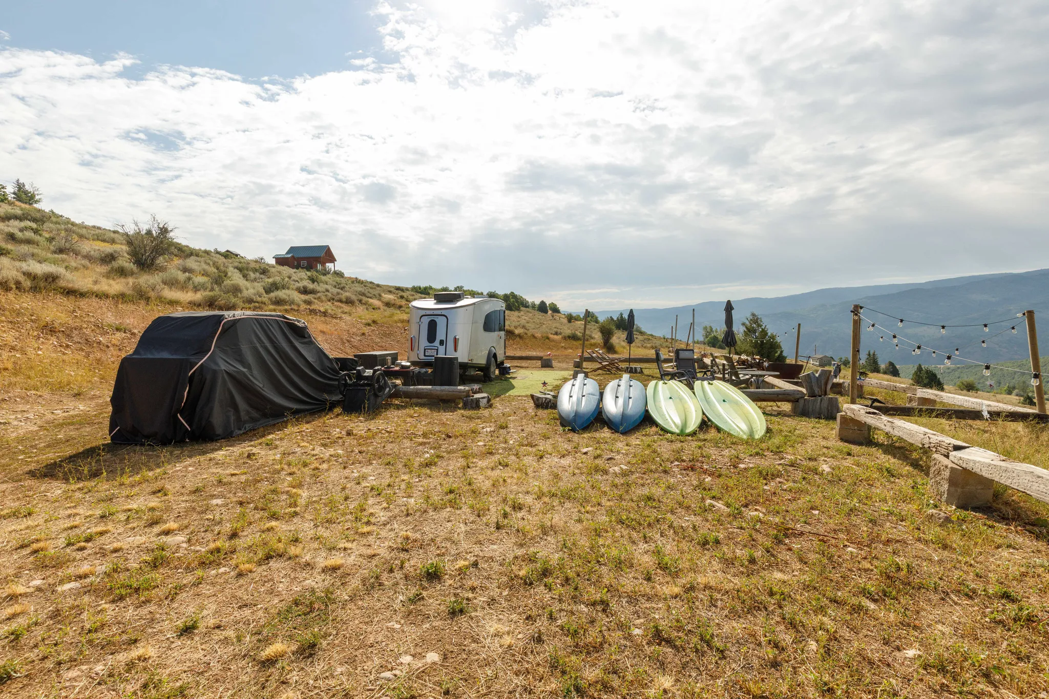 Terraced outdoor area featuring string lights and a distant cabin structure