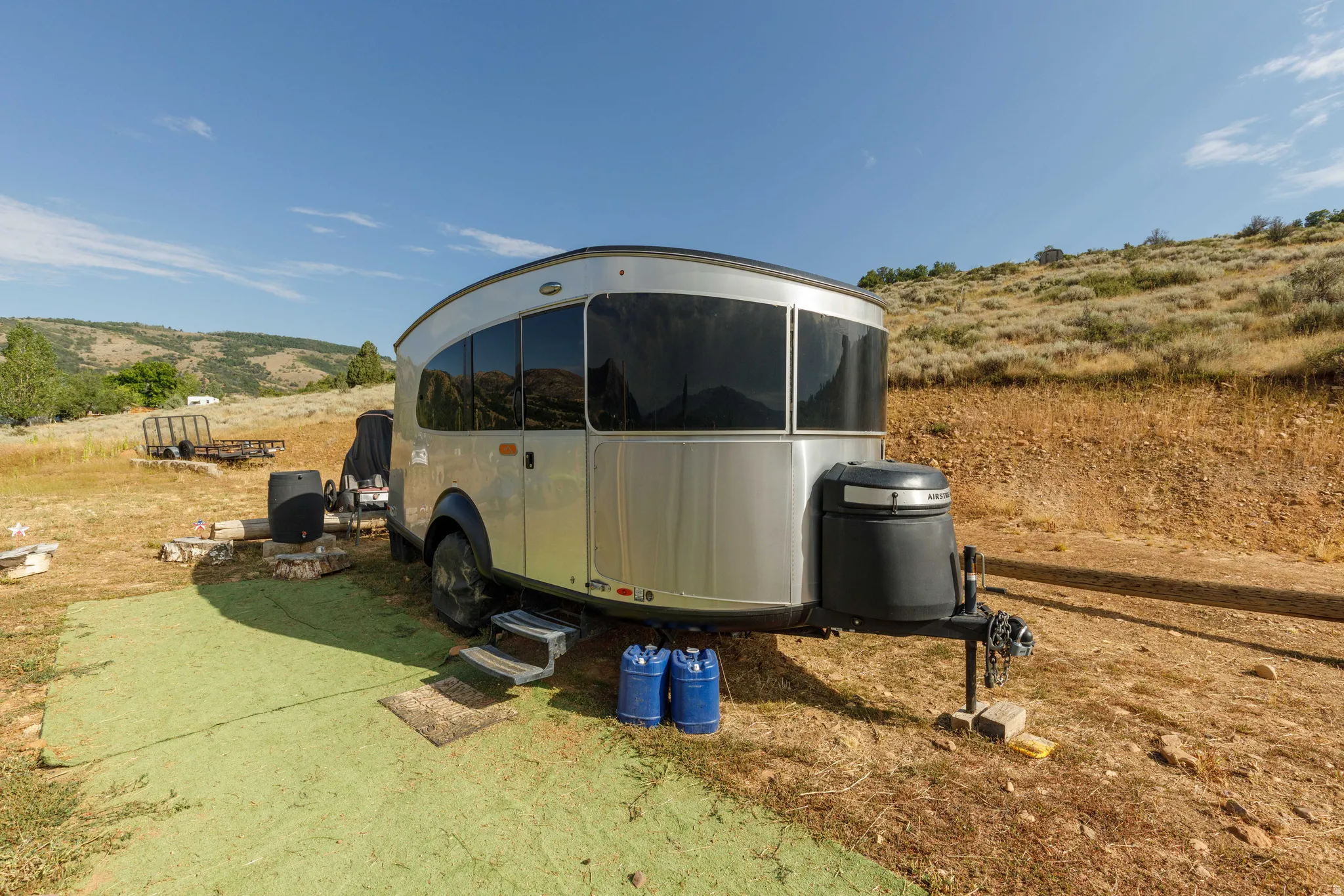 Silver recreational vehicle featuring tinted windows, a black front housing, and a multi-step entry