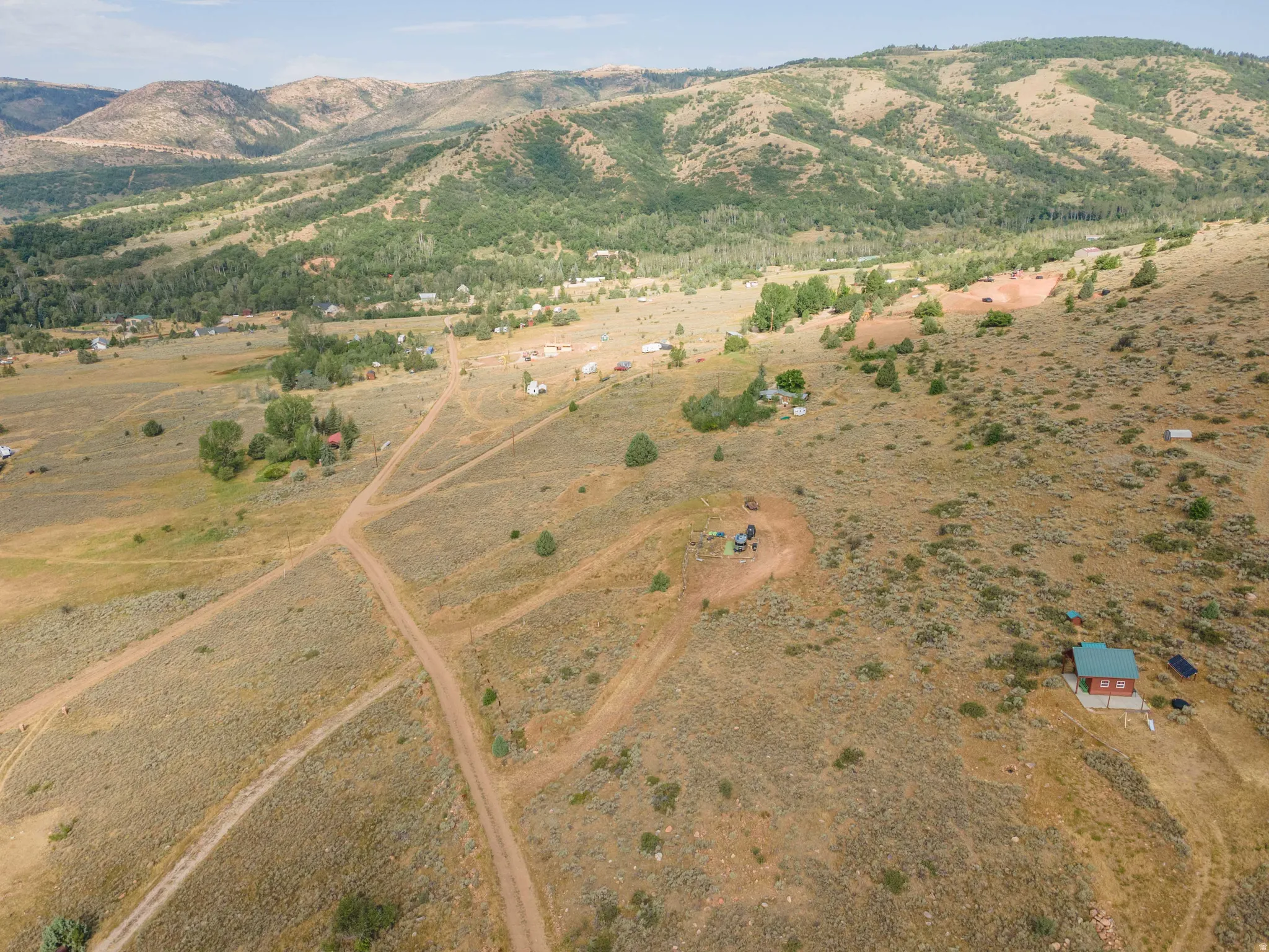 Expansive property featuring a scattered tree line, multiple dirt paths, and distant mountain ranges