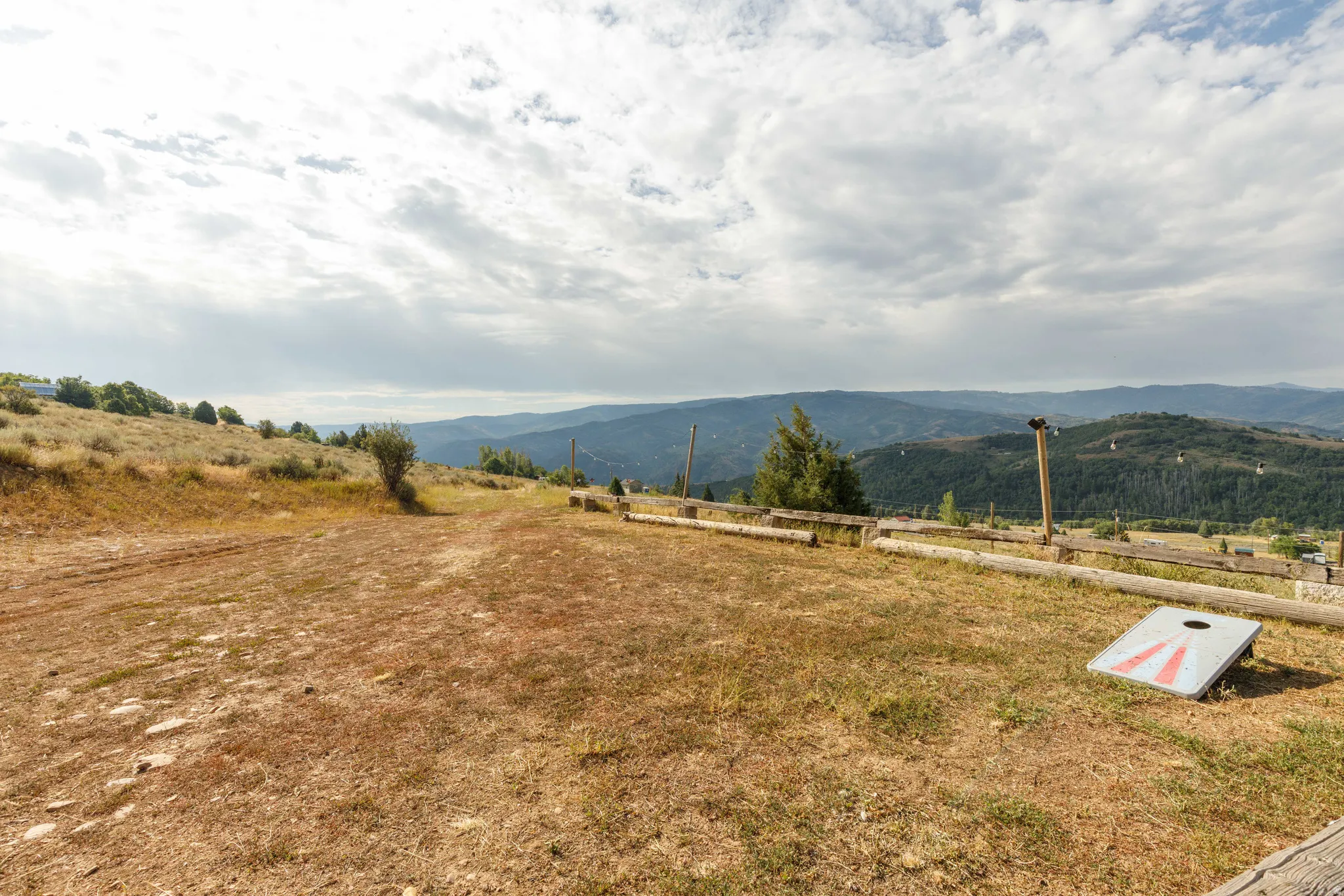 Expansive mountain landscape with rolling hills and distant ranges, featuring a natural terrain property with scattered brush and trees