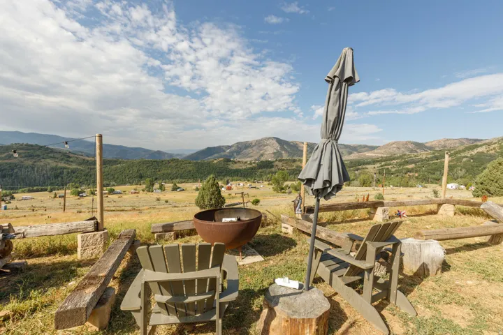 Outdoor area featuring a built-in fire pit, rough-hewn timber benches, and string lighting