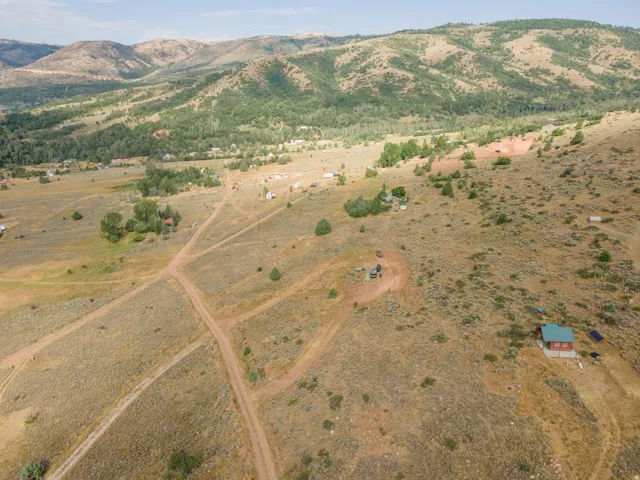 Expansive property featuring a scattered tree line, multiple dirt paths, and distant mountain ranges
