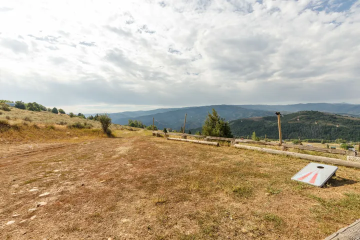 Expansive mountain landscape with rolling hills and distant ranges, featuring a natural terrain property with scattered brush and trees