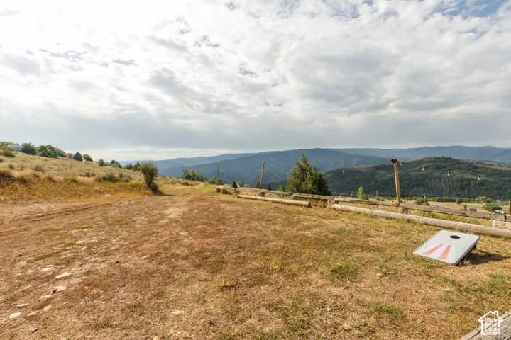 Expansive mountain landscape with rolling hills and distant ranges, featuring a natural terrain property with scattered brush and trees