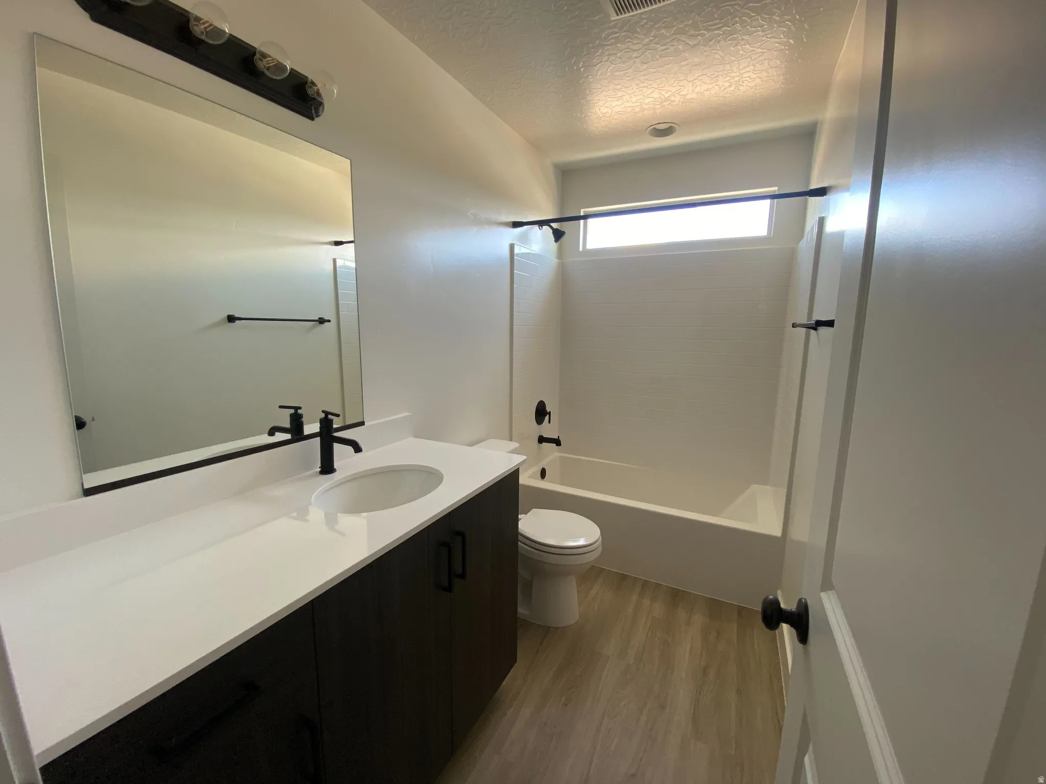Bathroom featuring a dark wood-finish vanity with a white countertop, undermount sink, and matte black fixtures
