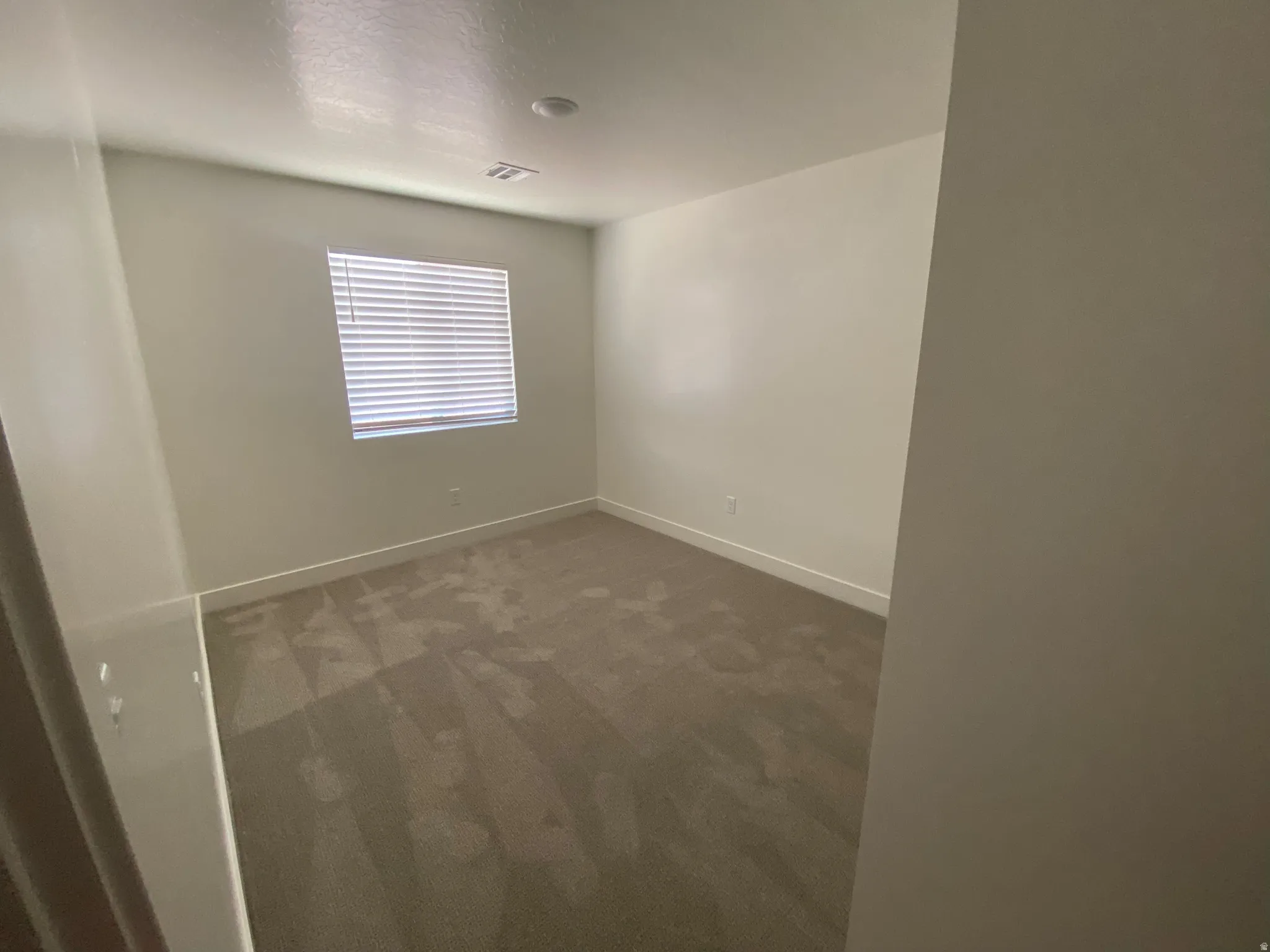 Interior room featuring light neutral wall tones and a window with horizontal blinds