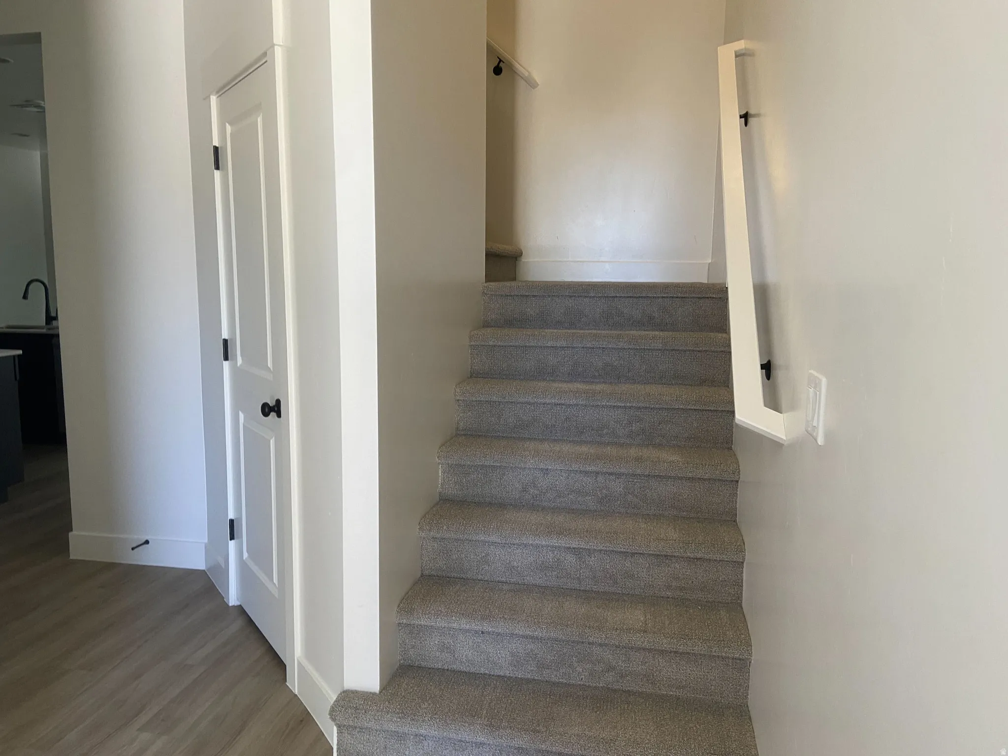 Carpeted staircase featuring a modern wall-mounted handrail