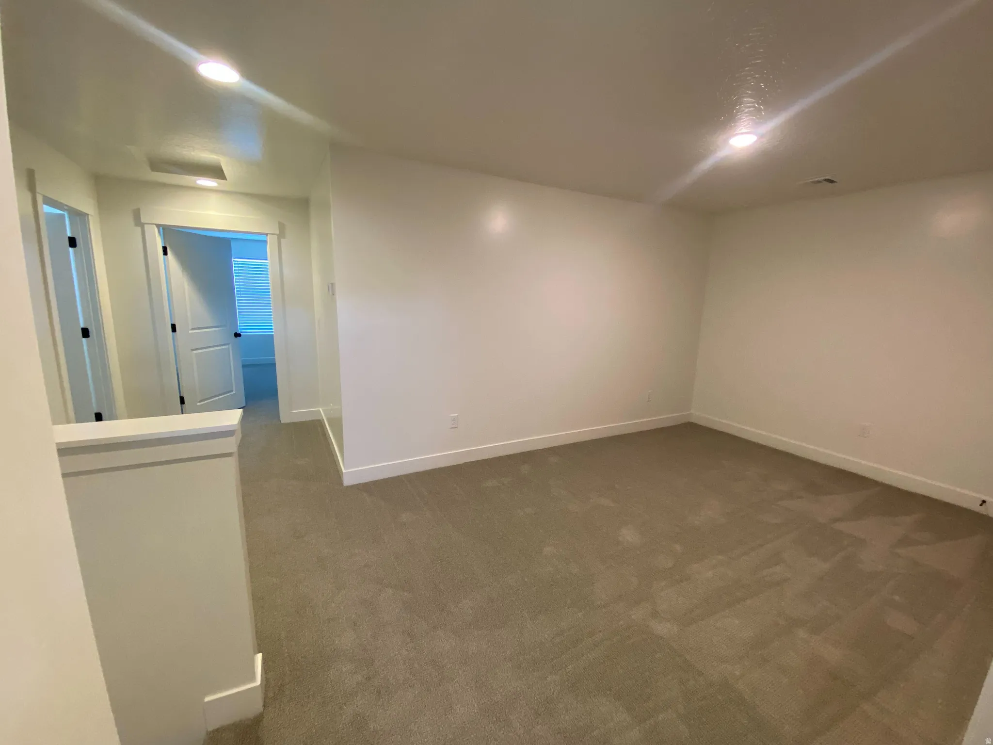 Carpeted room with recessed lighting and white baseboards