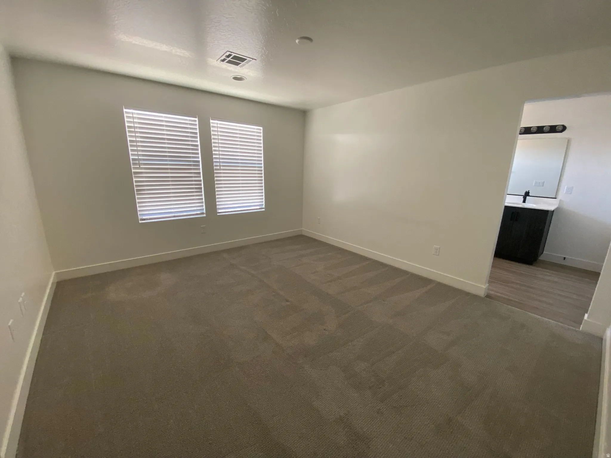 Carpeted interior space with two windows featuring blinds