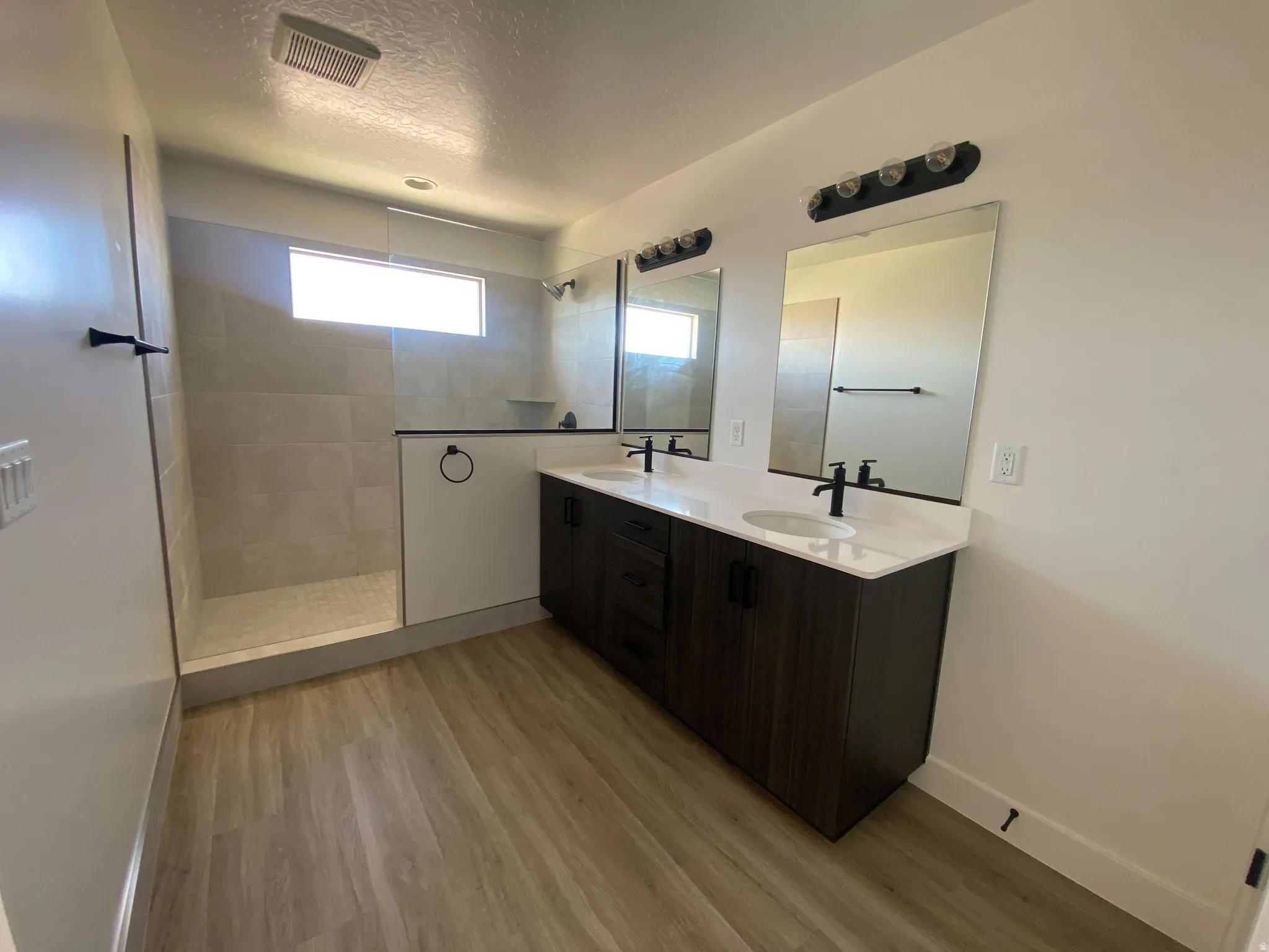 Spacious bathroom featuring a dual vanity with white countertops and dark wood-finish cabinetry