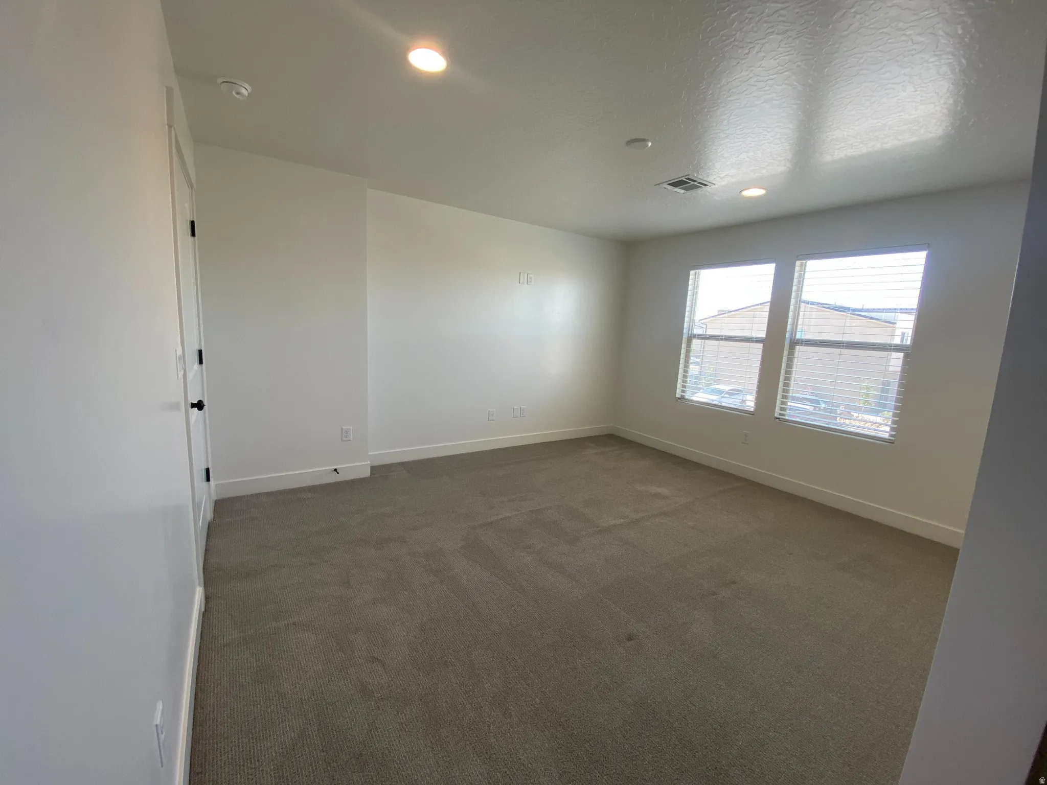 Bright room with two windows, recessed lighting, and neutral carpet flooring