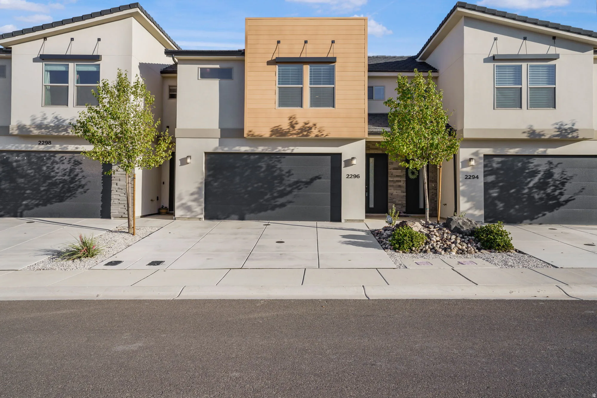 Modern townhome exterior featuring contemporary architectural lines, stucco siding, and dark garage doors