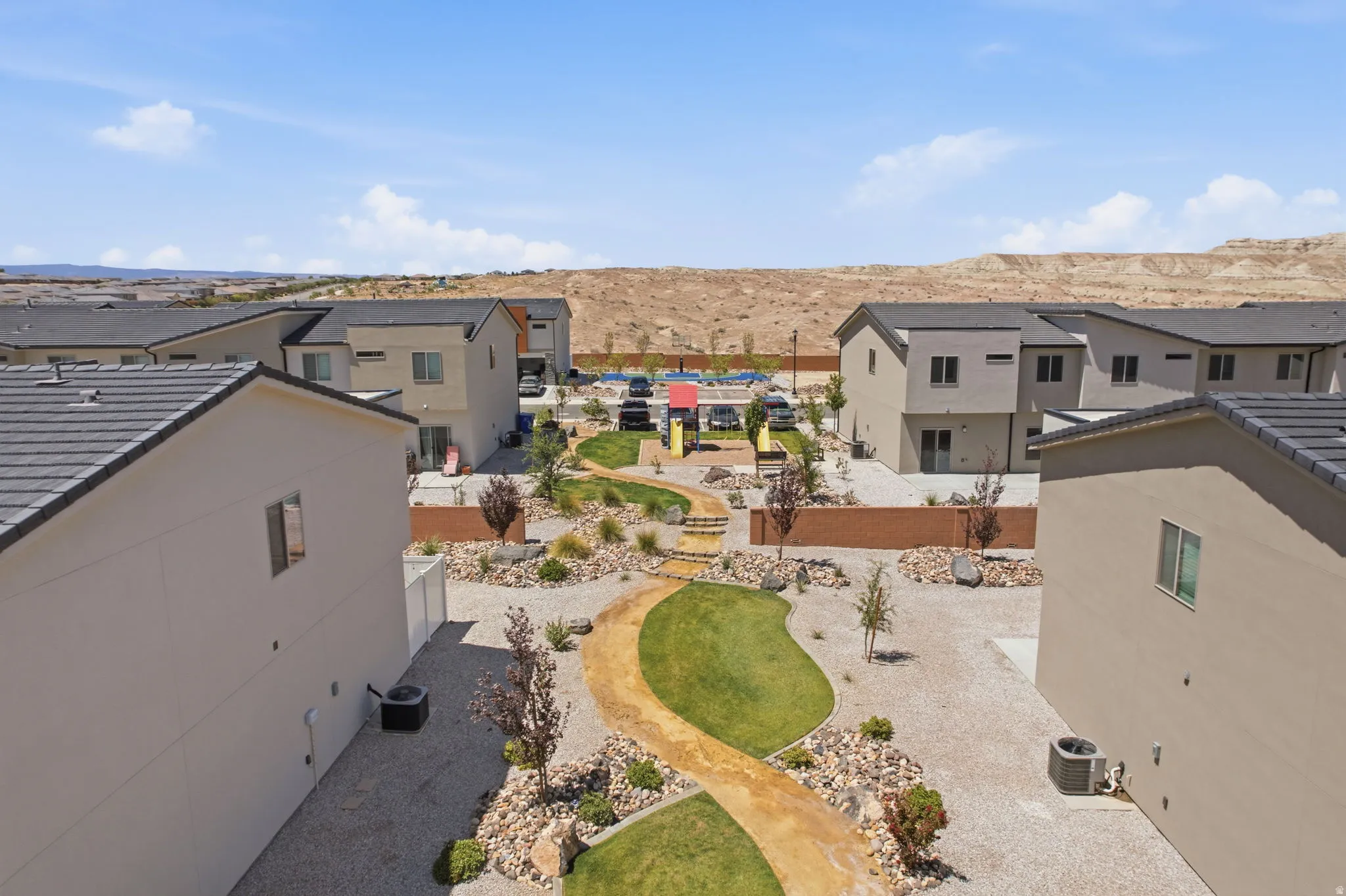 Landscaped community area featuring a winding pathway, varied plantings, and a playground with slides