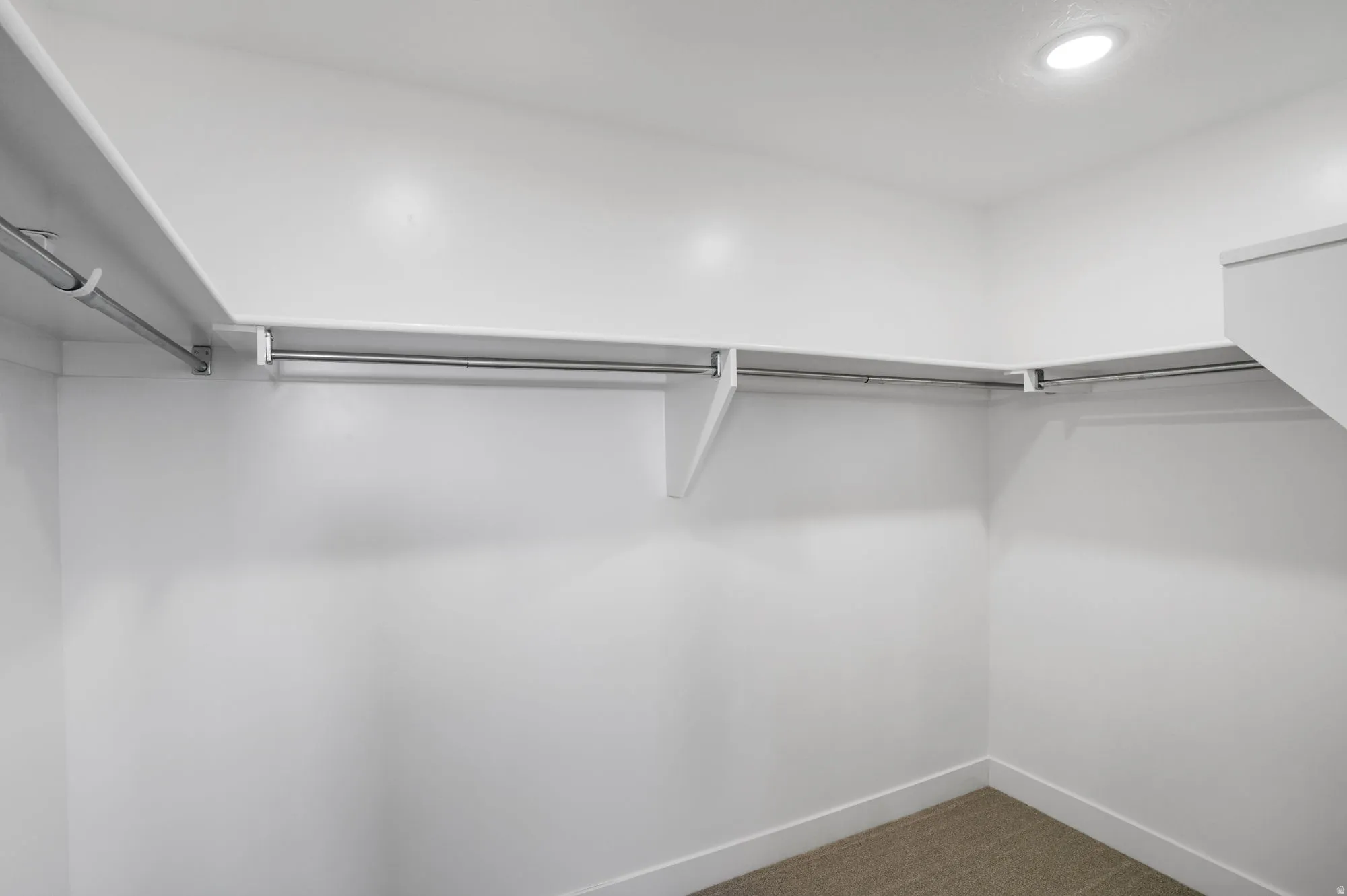 Spacious walk-in closet featuring white walls, ample shelving, and multiple clothing rods