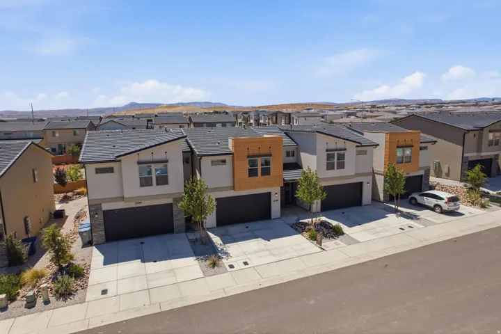 Modern townhome exteriors featuring light stucco, dark tiled roofs, and stone veneer accents