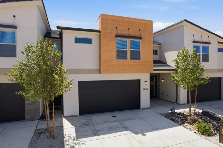 Modern townhome exterior featuring a wood-look facade accent, stucco siding, and a two-car garage