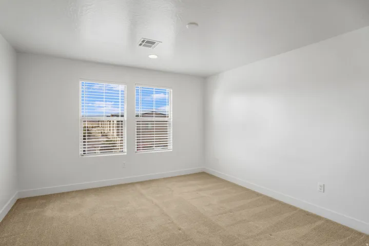 Bright room featuring two windows with white blinds, neutral carpeting, white walls, and recessed lighting