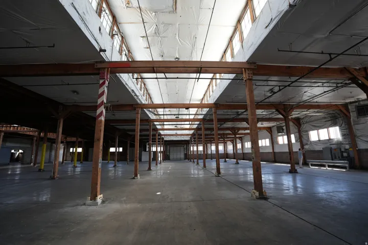 Expansive industrial interior featuring exposed wood beams and concrete flooring