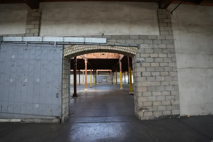Spacious interior featuring exposed timber beams, concrete block walls, and a brick archway