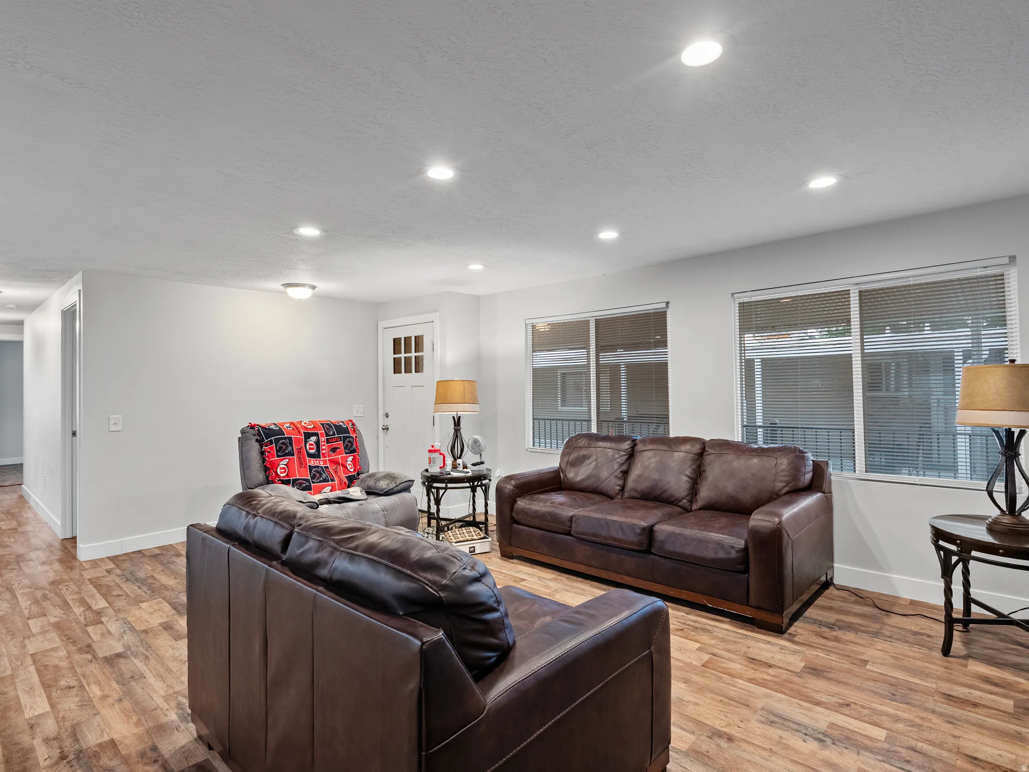 Spacious living area featuring wood-finish flooring, recessed lighting, and multiple windows