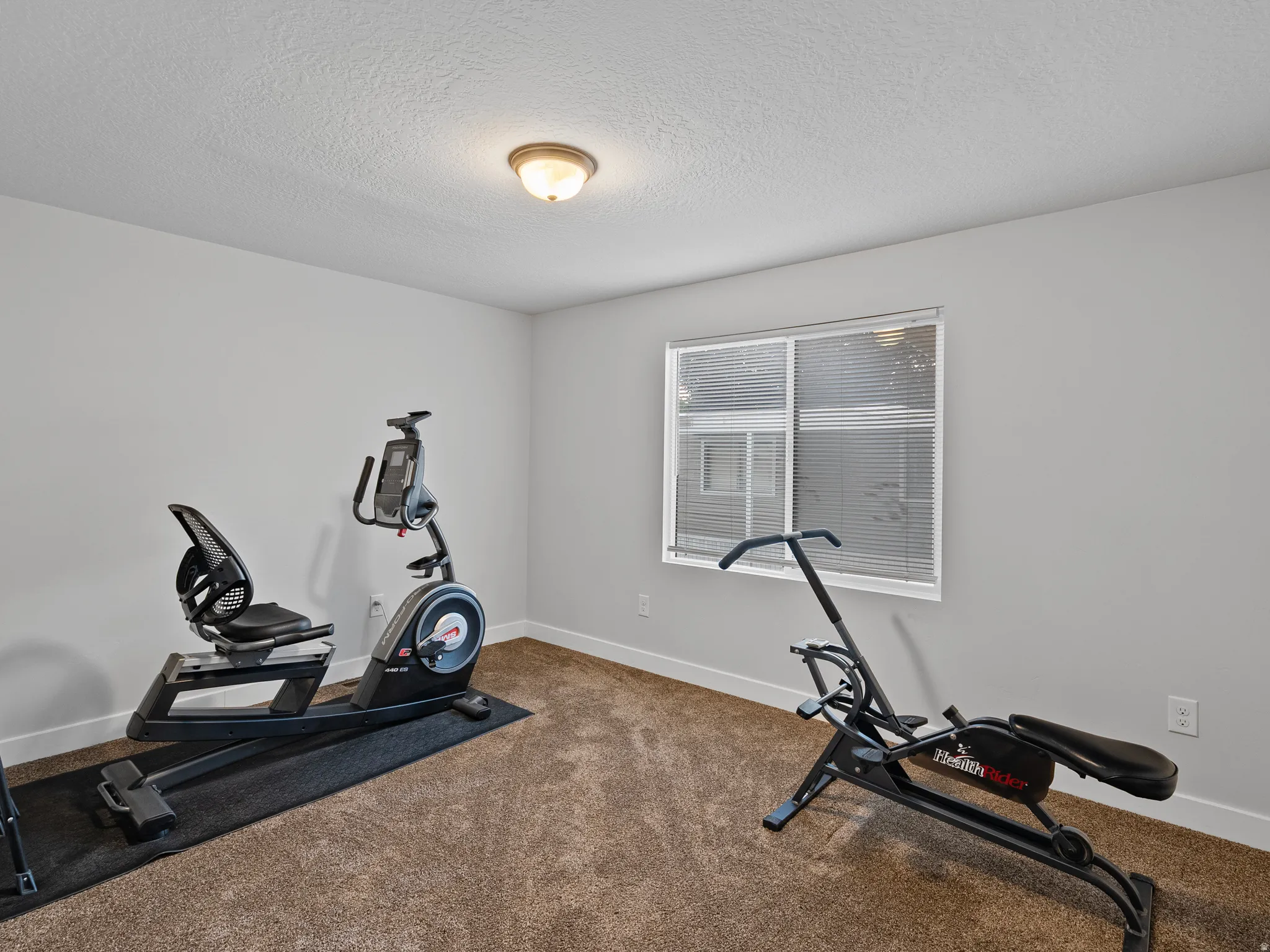 Interior room featuring light gray walls, a textured ceiling, and brown carpeting