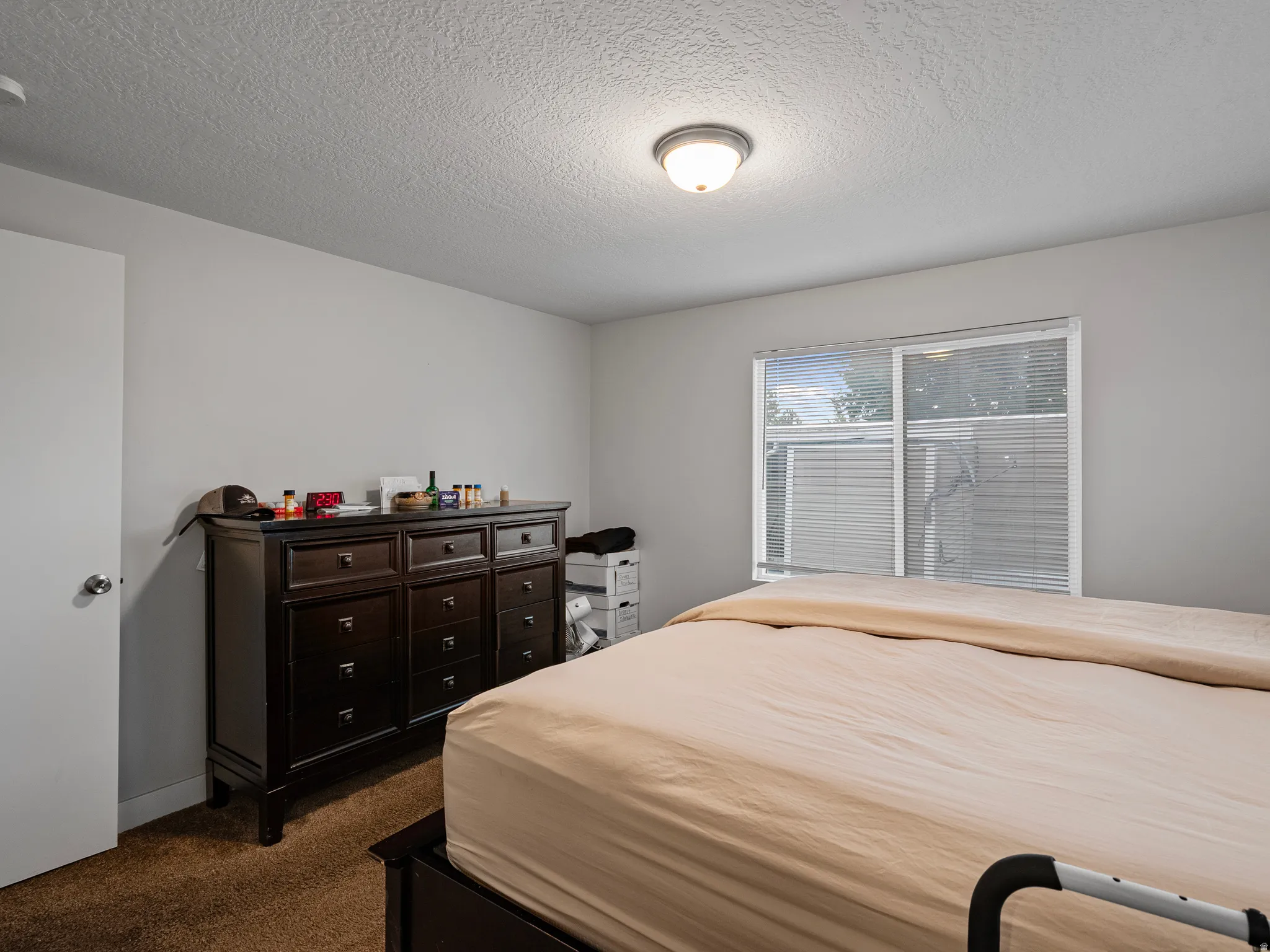 Bedroom featuring light gray walls, textured ceiling, and a flush mount ceiling light fixture