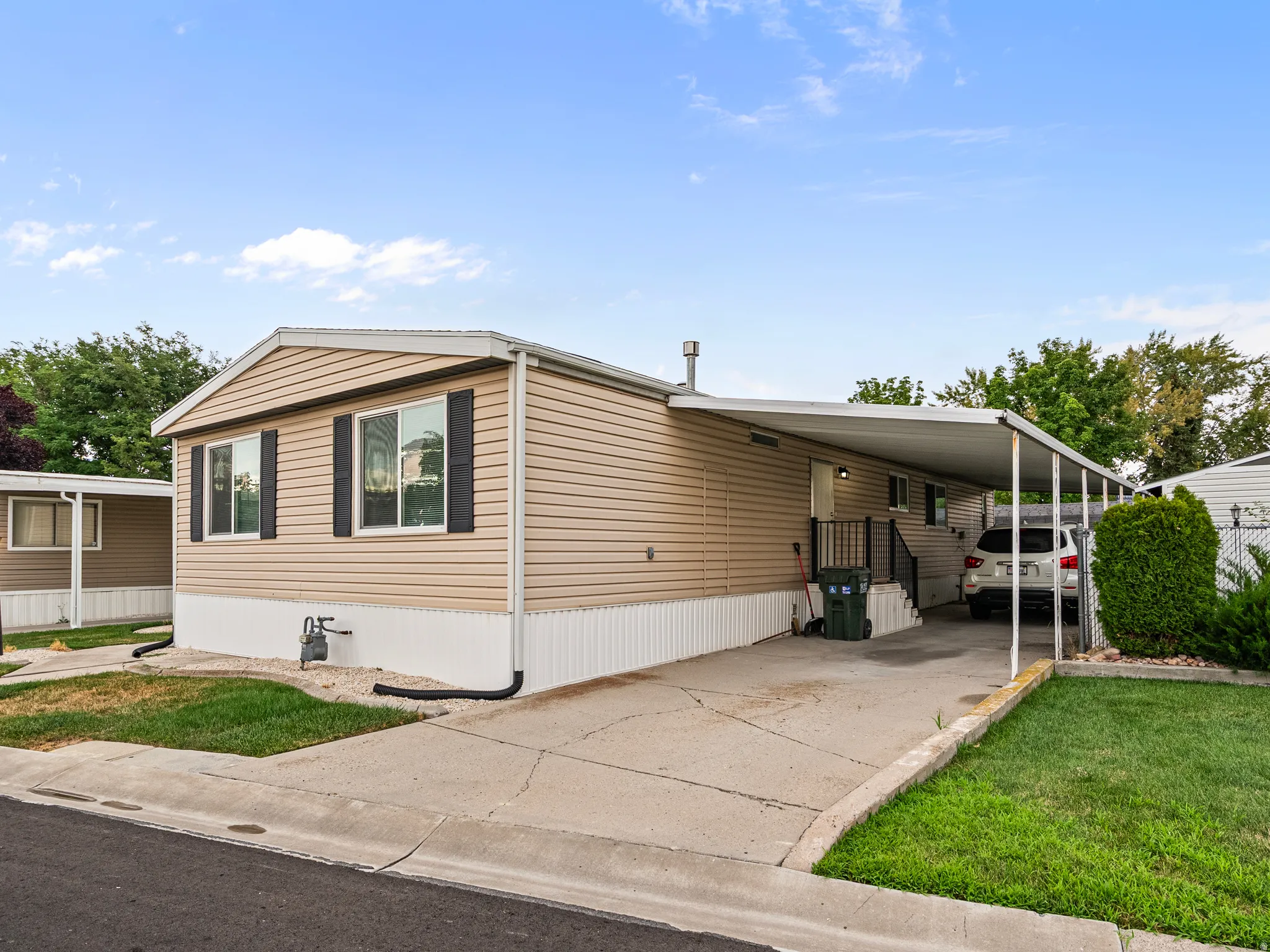 Property exterior featuring tan siding, white trim, and black window shutters