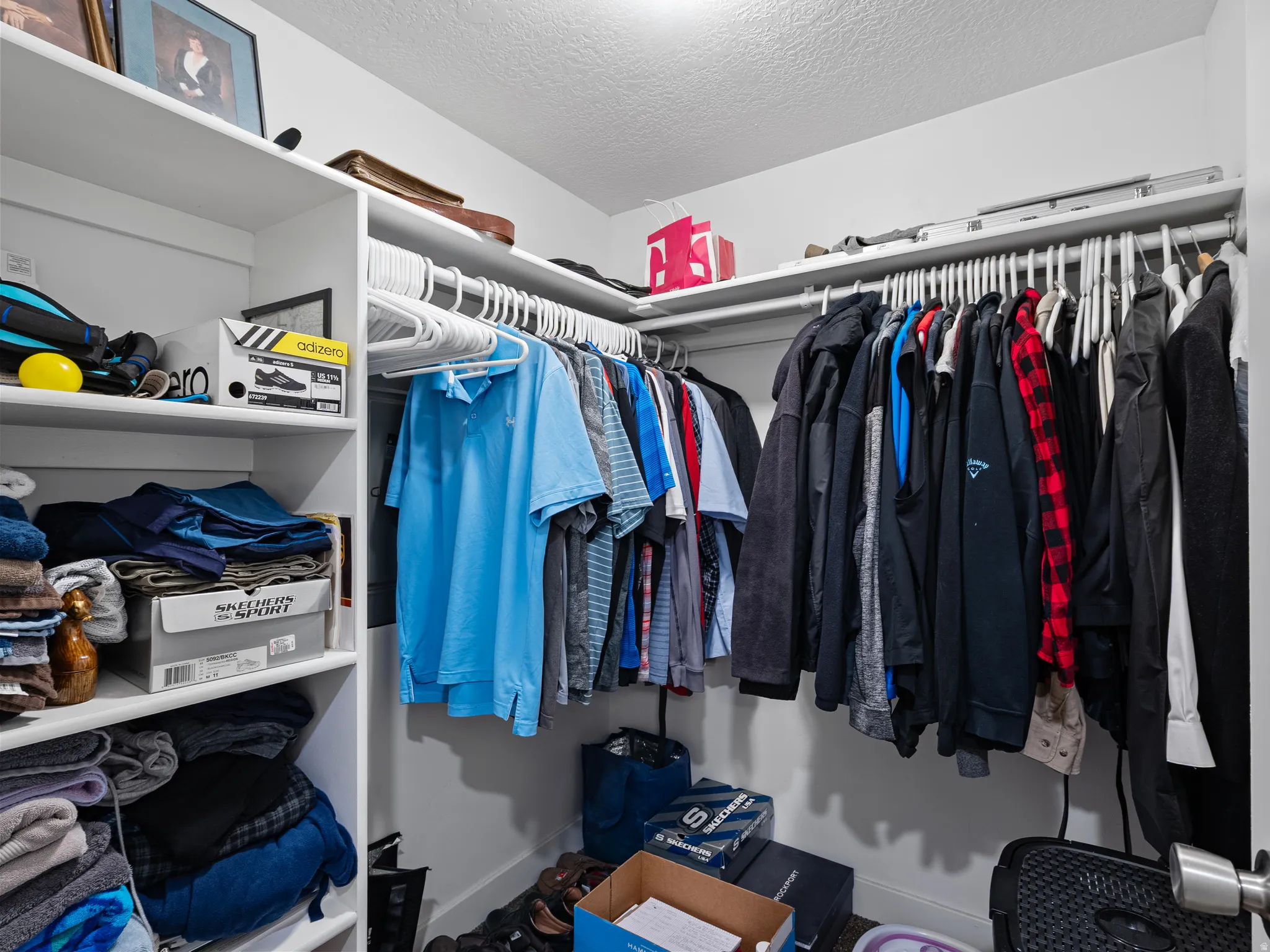 White walk-in closet featuring built-in shelving, multiple hanging rods, and ample storage space