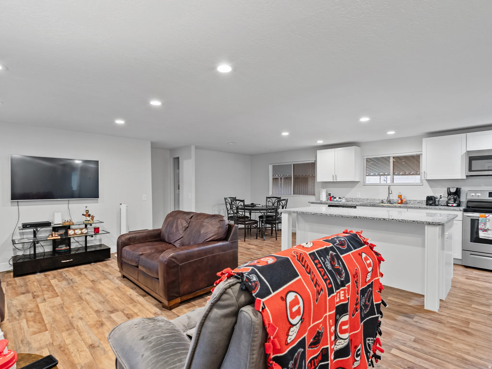 Open-concept living space featuring wood-finish flooring, recessed lighting, and a kitchen island with a light-colored countertop
