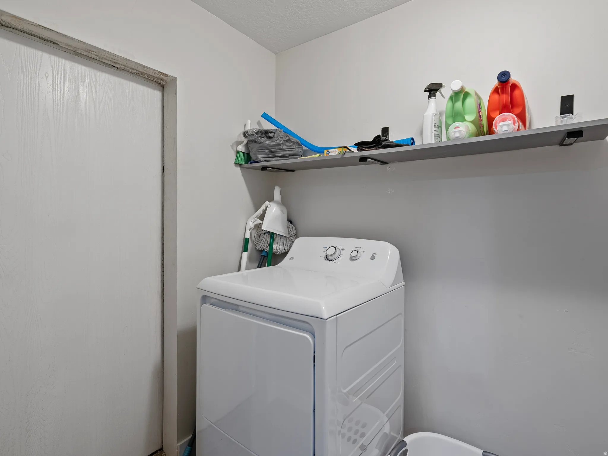 Dedicated laundry area featuring a built-in shelf for storage