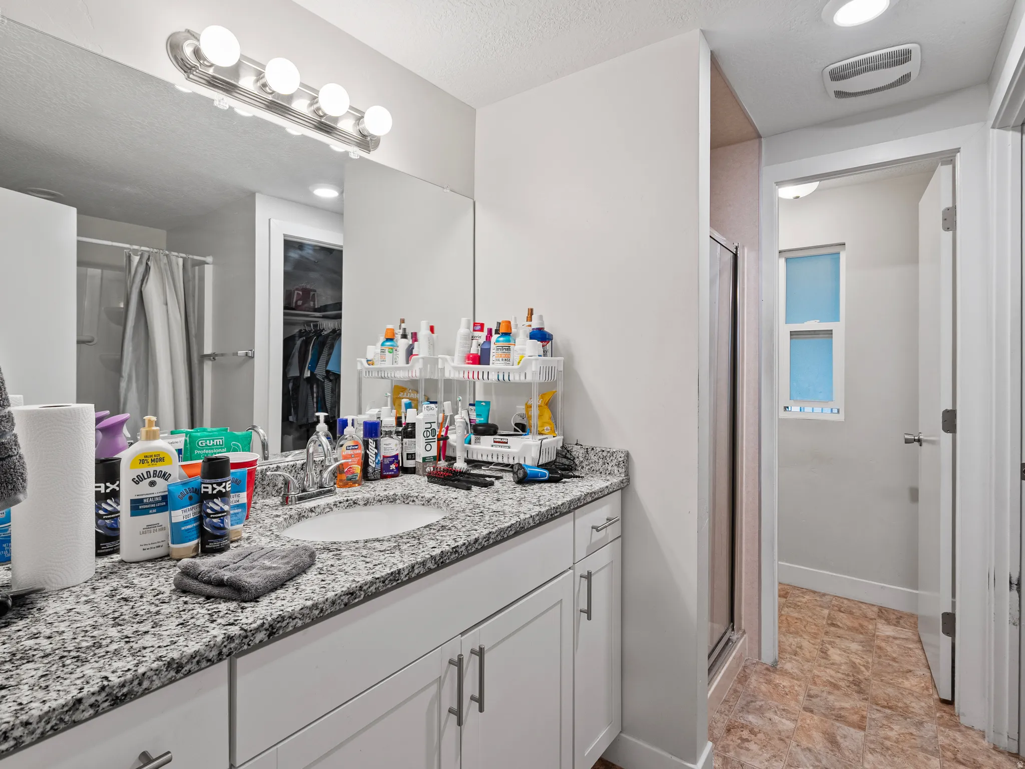 Bathroom vanity featuring a speckled countertop, integrated sink, and white cabinetry