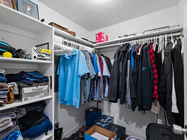 White walk-in closet featuring built-in shelving, multiple hanging rods, and ample storage space