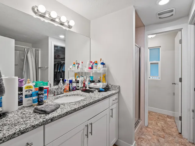 Bathroom vanity featuring a speckled countertop, integrated sink, and white cabinetry