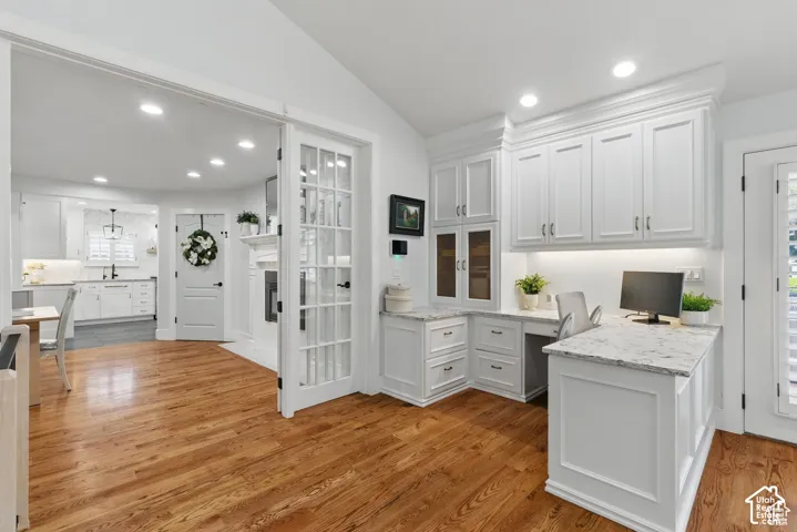 Dedicated office space featuring built-in white cabinetry, granite countertops, and under-cabinet lighting
