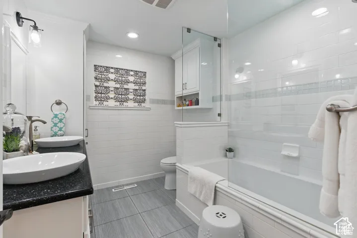 Master Bathroom featuring a dual vanity with vessel sinks, dark speckled countertops, and under-cabinet storage