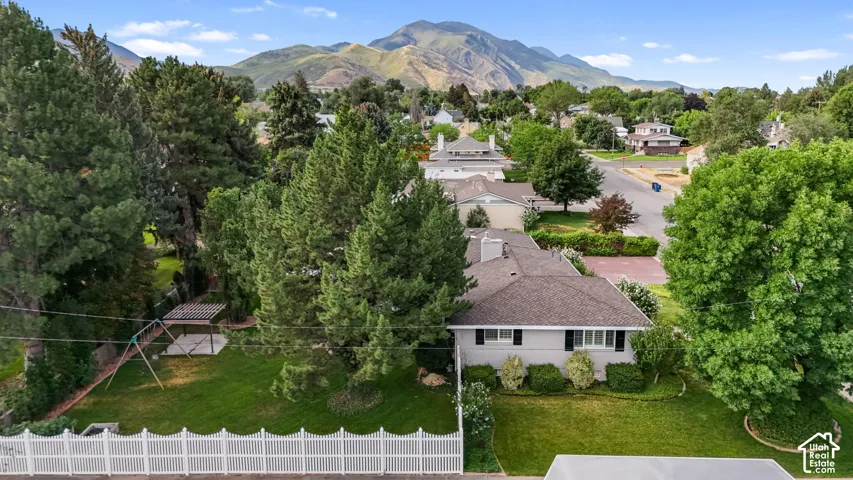 Aerial perspective of a single-story residence with a gray exterior, dark shingled roof, and black window shutters