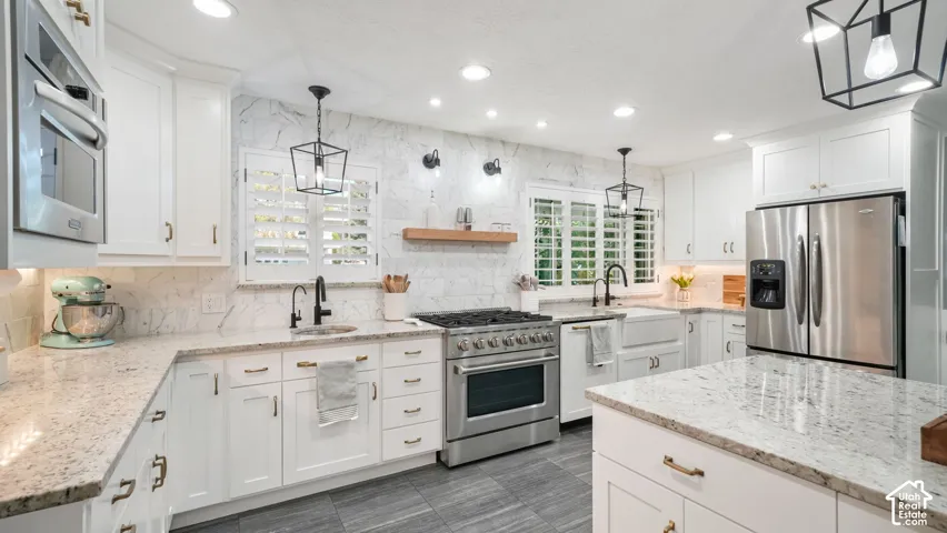 Kitchen featuring white cabinetry, granite countertops, stainless steel appliances, a farmhouse sink, and a tiled backsplash