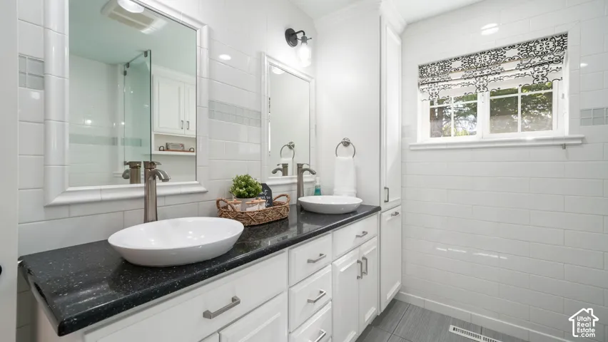 Master-Dual vessel sinks set atop a dark speckled countertop with white cabinetry and brushed nickel hardware