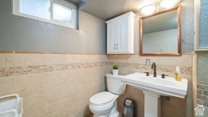 Pedestal sink with a matte black faucet, framed mirror, and integrated lighting