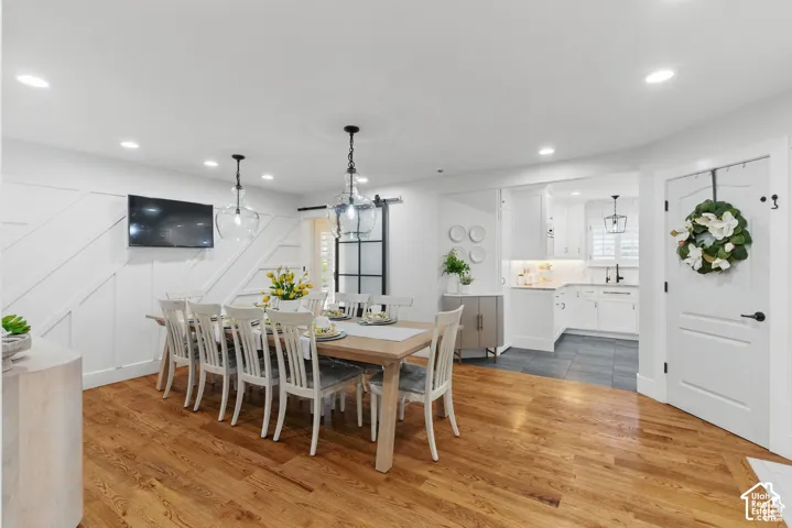 Spacious dining area featuring wood-finish flooring, recessed lighting, and decorative wall paneling