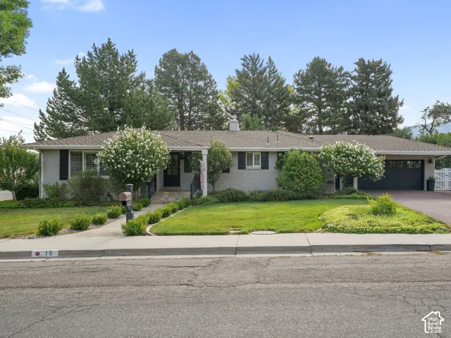 Ranch-style residence featuring a light gray exterior, black window shutters, and a dark asphalt shingle roof