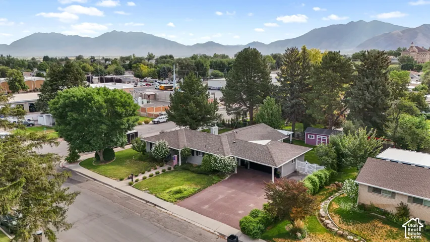 Ranch-style residence featuring a brown shingle roof and a paved driveway