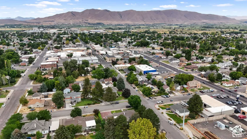 Expansive aerial perspective showcasing a town with residential and commercial properties, surrounded by natural terrain